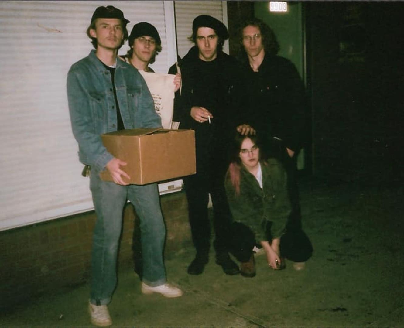 Dead Friends NAIT Band five bandmates pose at night in front of garage holding boxes