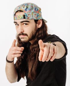 Man wearing colourful hat pointing at camera