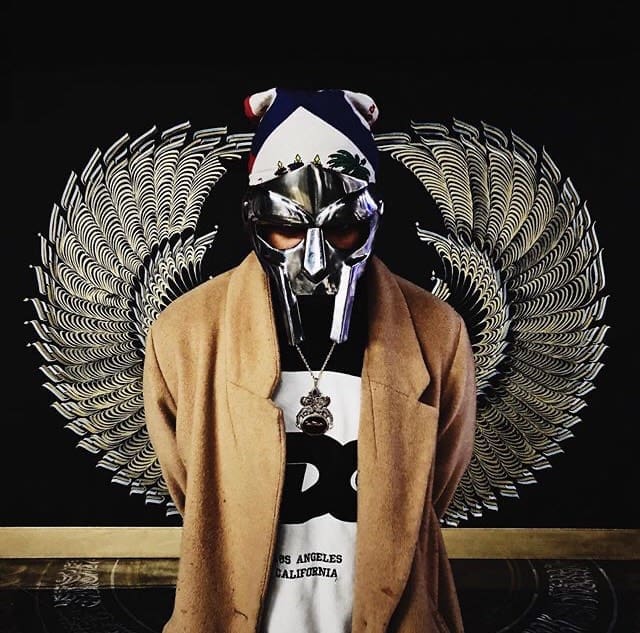 man poses in peacoat with silver mask