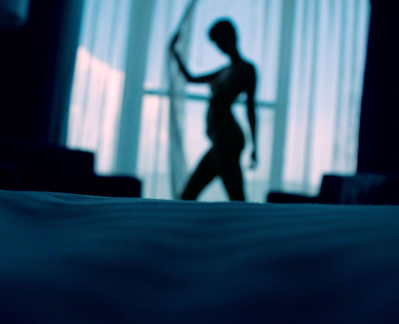 Girl in shadows opening blinds