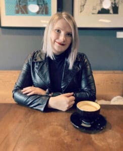 woman sits at table in coffee shop with coffee in front of her