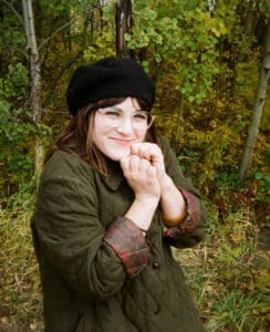 Woman stands in forest smiling