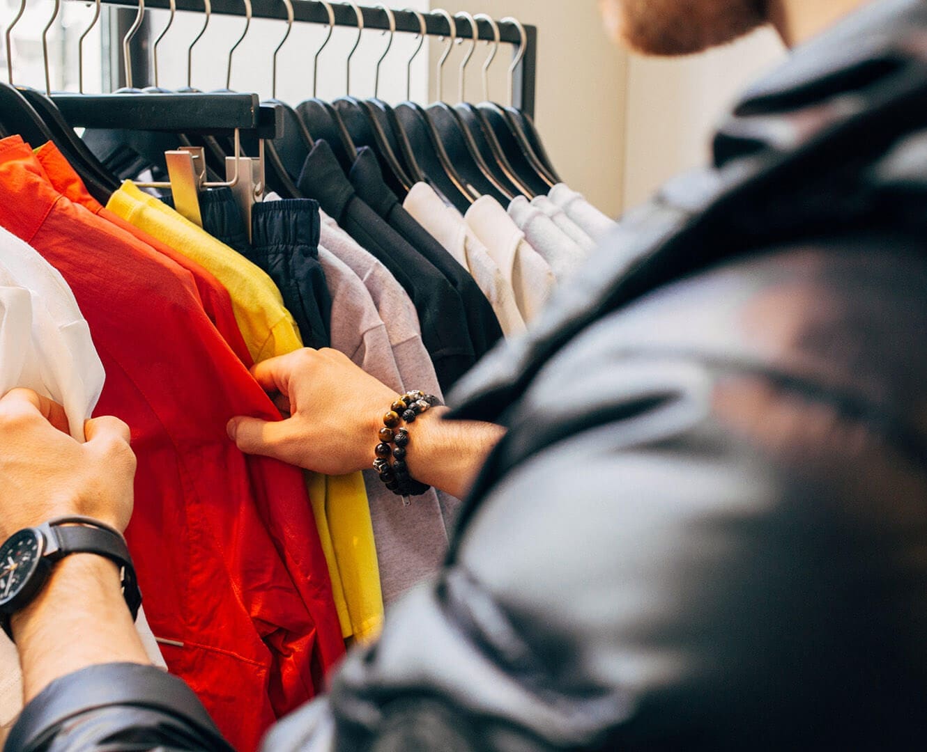 Man browses through clothing racks at store