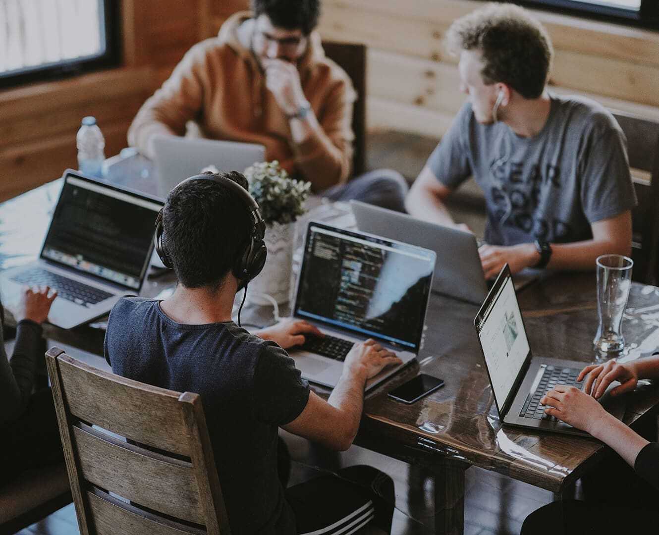 three men still at a table working on their laptops together