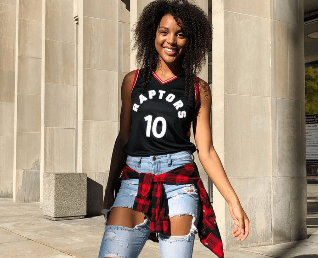 Woman stands wearing raptors jersey in Toronto Ontario
