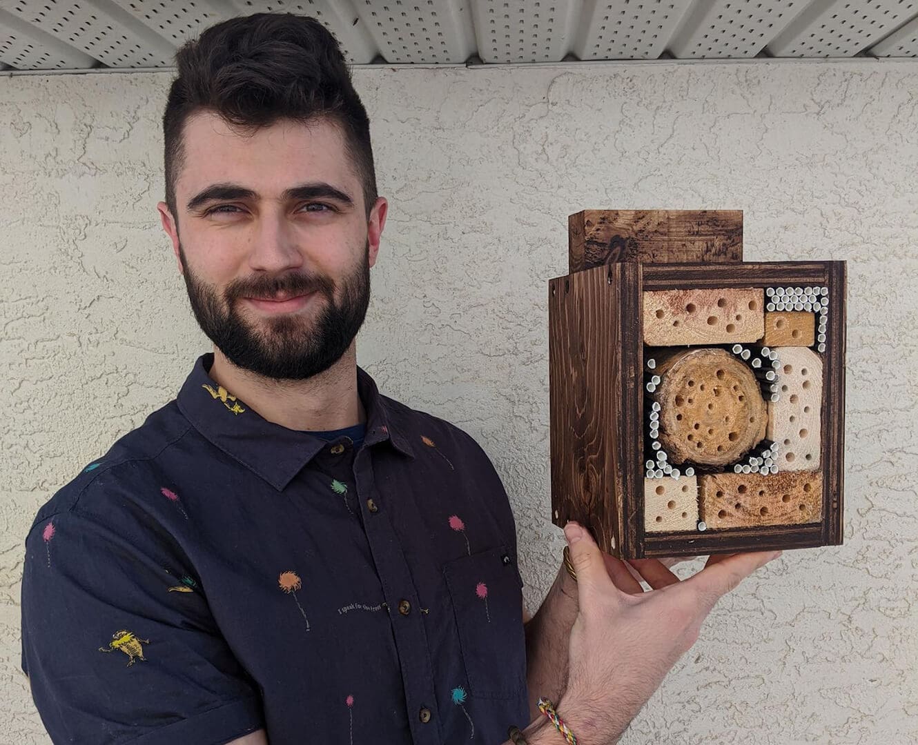 Man holds handmade bee hotel.