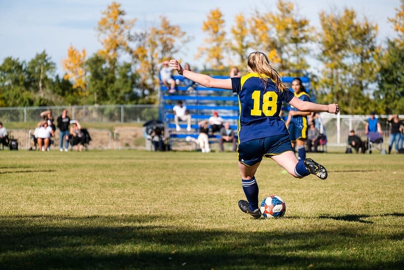 blonde woman kicking soccer balll