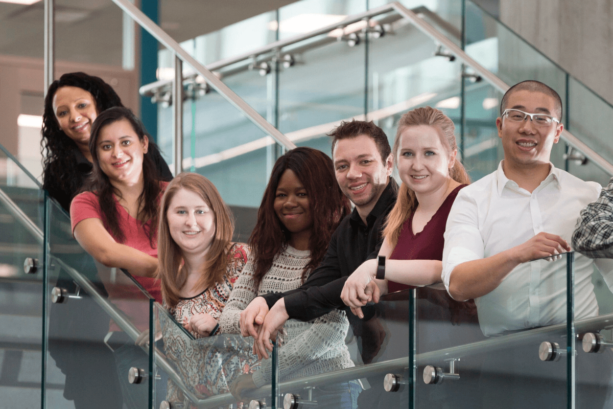 Seven students standing on a staircase. The photo is of NAITSA's 2021/22 Senate.