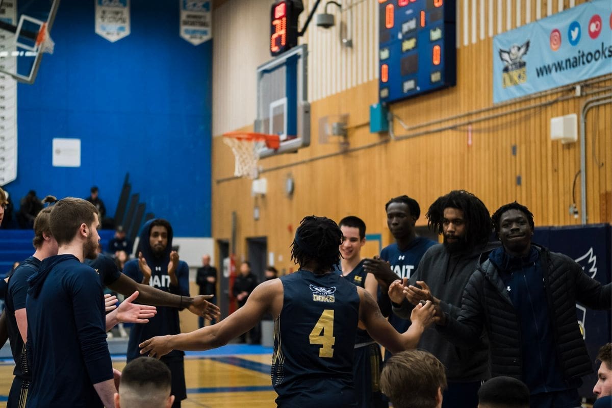 Benjamin Kamba, number 4, claps hands with the other players on the team.