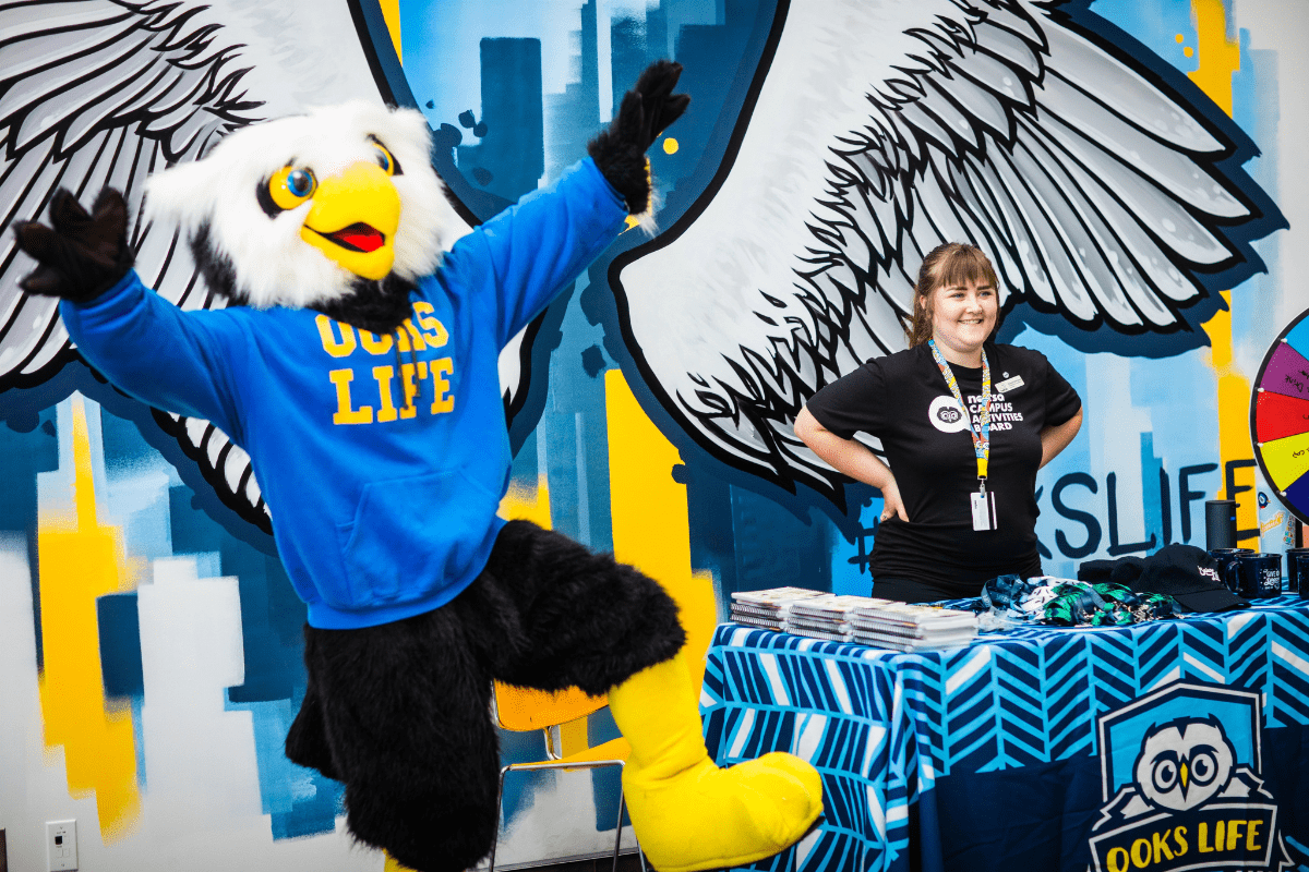 The NAITSA Ooks Life Mascot with its hands in the air in a fun pose.