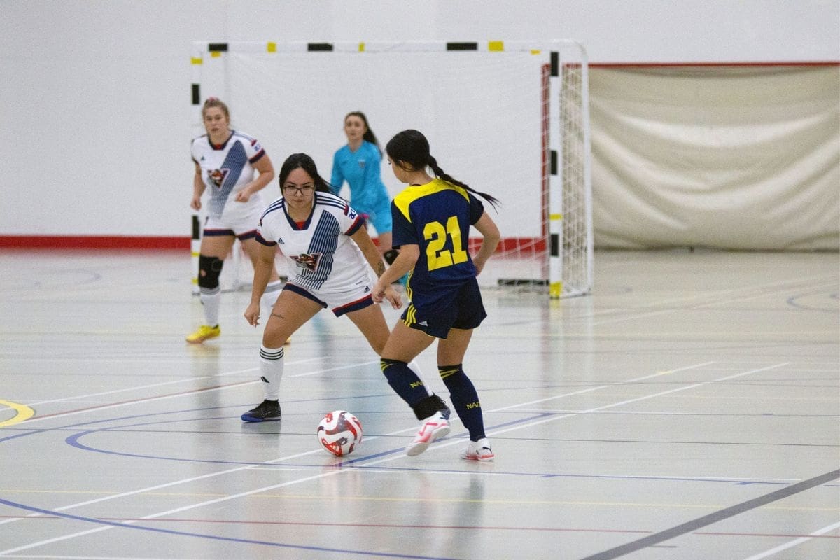 Untitled design (5) Women from two opposing teams play futsal, a type of soccer played indoors.