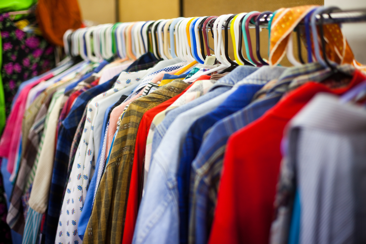 colourful clothing hangs on plastic hangers on a rack