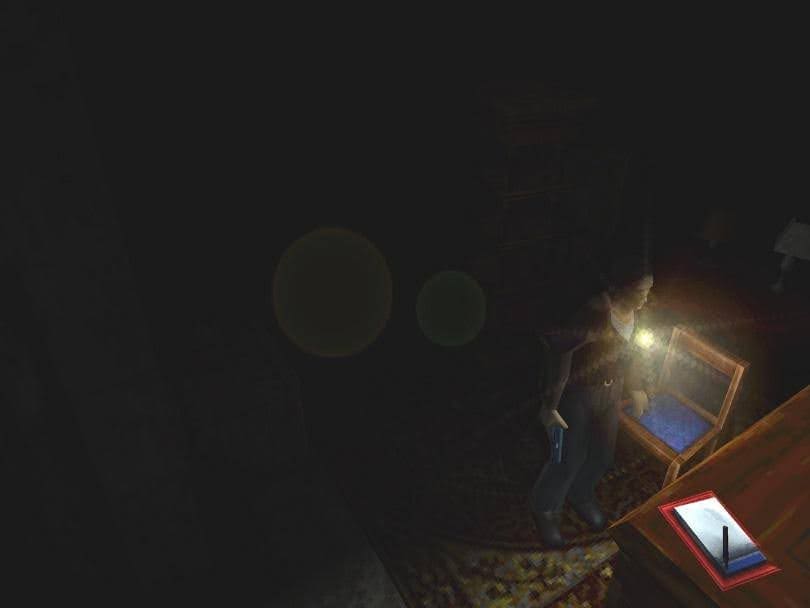 screenshot from the game silent hill. the screen is mostly black except for a small light coming from the player character's flashlight in the bottom right corner. it's eerie and spooky.