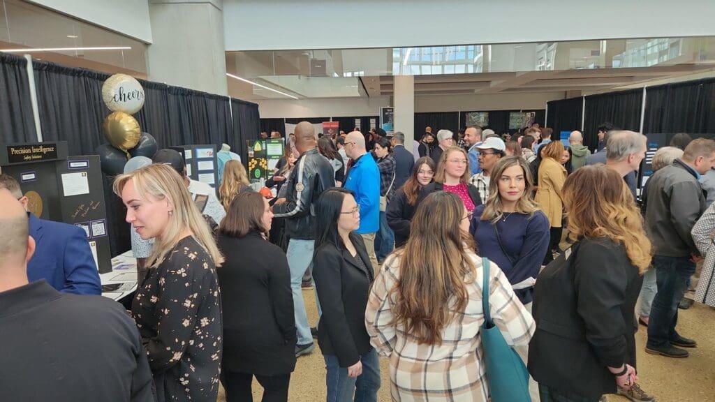 A group of people look at booths at a trade-show style exhibit. 