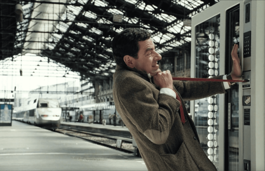 mr bean's tie is stuck in a baguette machine and he pulls at it 
