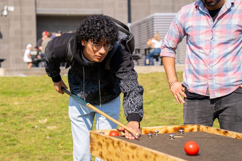 A man leans over a pool table, lining up his shot. 