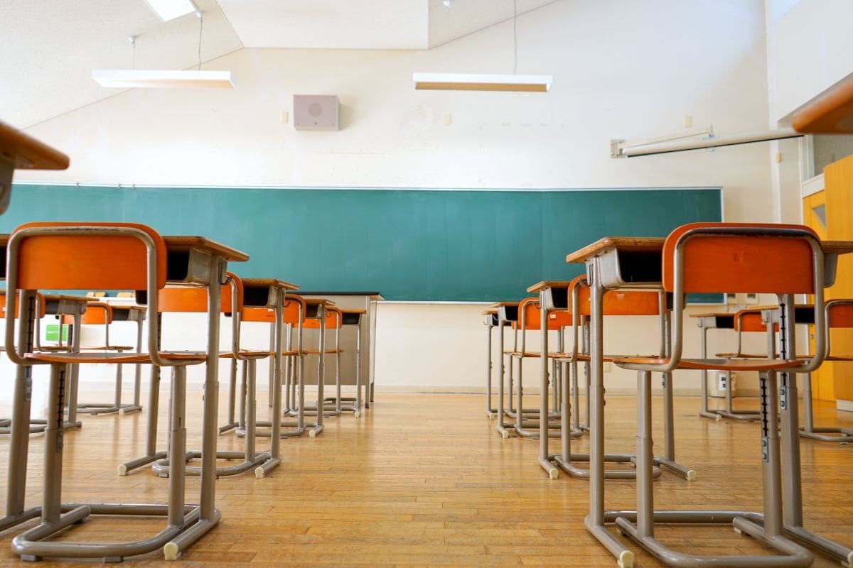 an empty classroom with orange chairs and desks
