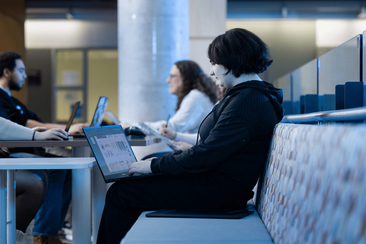 A student sits with a laptop on NAIT campus.